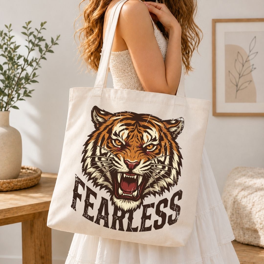 Person holding a tote bag with a tiger design and 'FEARLESS' text in a home setting.