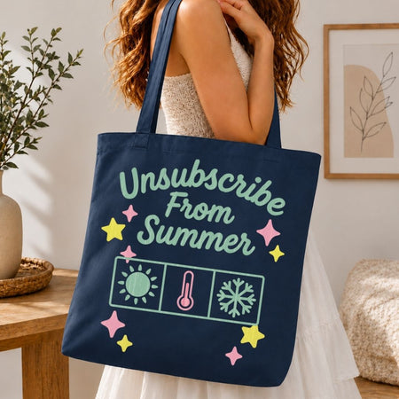Person holding a navy tote bag with 'Unsubscribe From Summer' text and graphics in a home setting.