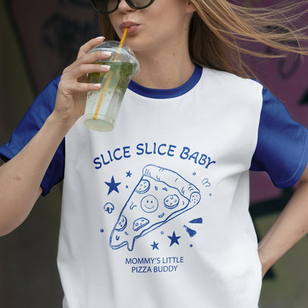Person wearing a white and blue t-shirt with pizza design and text, drinking from a clear cup.