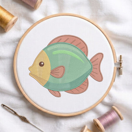 A circular embroidery hoop holds white fabric with a stylized fish design in mint green, peach, and mustard yellow. Spools of thread and a needle are arranged around it on a white fabric background.