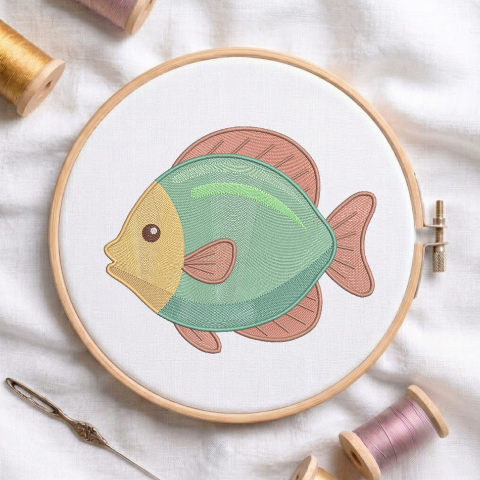 A circular embroidery hoop holds white fabric with a stylized fish design in mint green, peach, and mustard yellow. Spools of thread and a needle are arranged around it on a white fabric background.