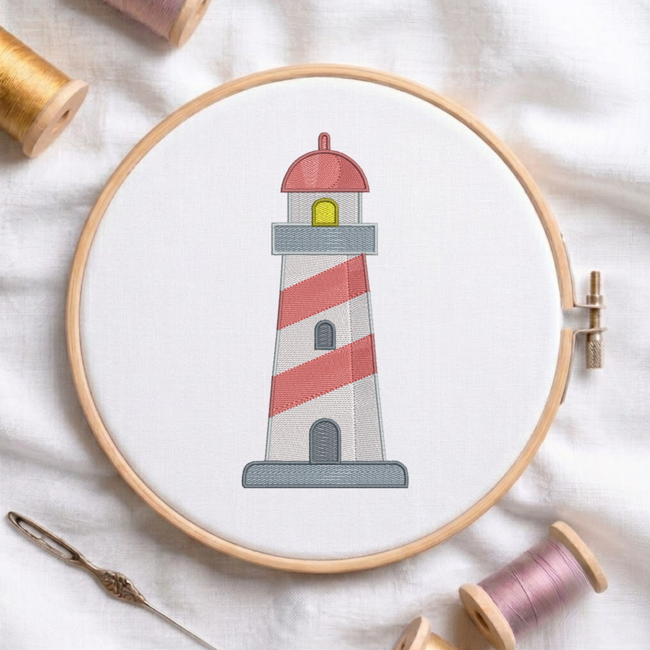 A circular embroidery hoop holding white fabric with a stitched lighthouse design. The lighthouse has red and white diagonal stripes, a gray base, a red dome, and a small yellow window.