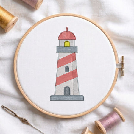 A circular embroidery hoop holding white fabric with a stitched lighthouse design. The lighthouse has red and white diagonal stripes, a gray base, a red dome, and a small yellow window.