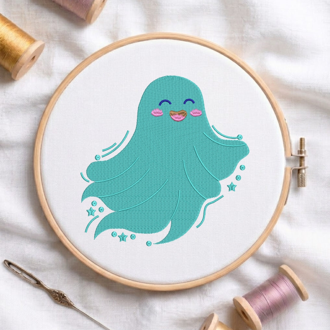 A wooden embroidery hoop holding white fabric with a cute teal octopus design stitched inside. The hoop is styled on a white fabric background with spools of thread and a needle nearby.