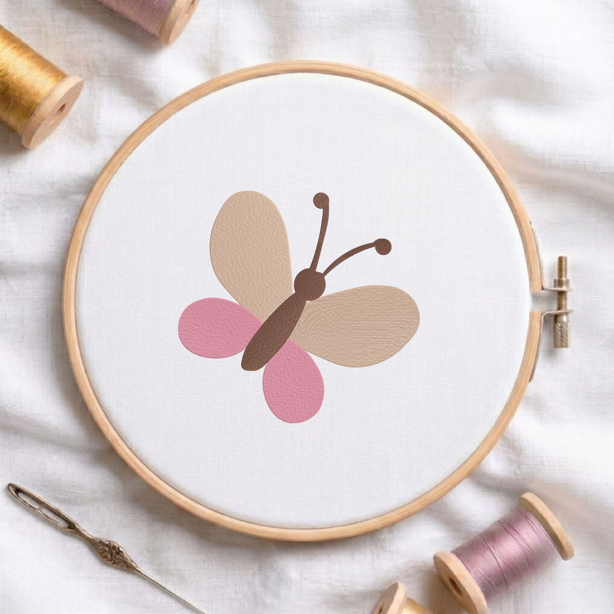 Minimalist cute butterfly machine embroidery design shown in a wooden embroidery hoop on white fabric with thread spools and a needle