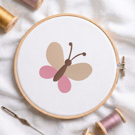 Minimalist cute butterfly machine embroidery design shown in a wooden embroidery hoop on white fabric with thread spools and a needle