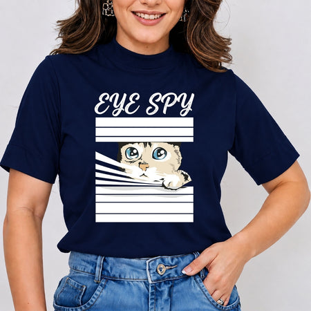Woman wearing a navy blue mock neck t-shirt featuring a cute cartoon graphic of a cat peeking through white window blinds with the text "EYE SPY", tucked into jeans.