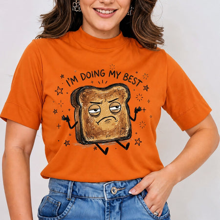 Smiling person wearing an orange t-shirt featuring a funny grumpy burnt toast character and the relatable quote "I'M DOING MY BEST".
