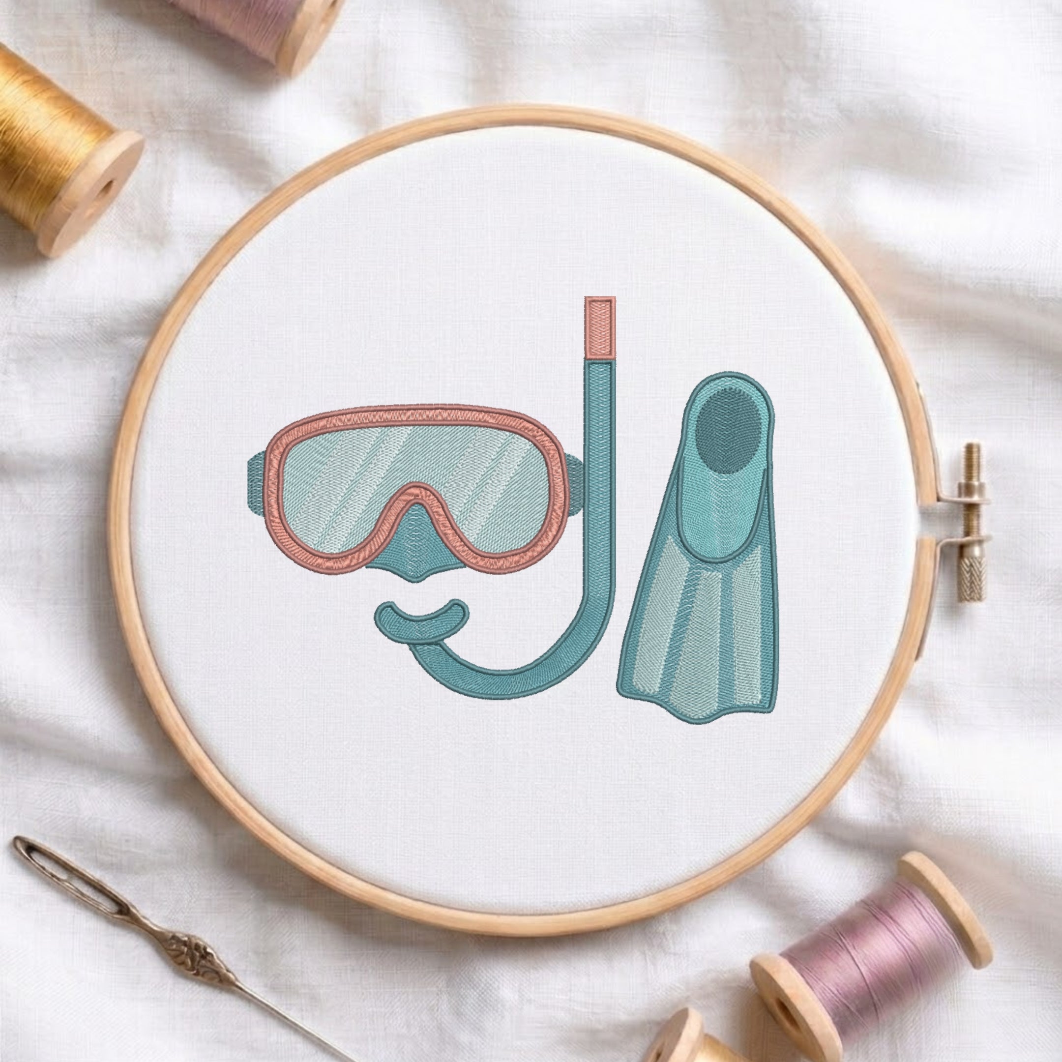 Snorkel, mask, and flipper machine embroidery design displayed inside a round wooden embroidery hoop with thread spools.