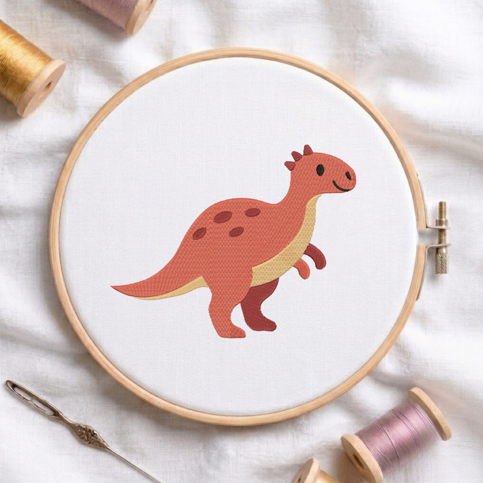 An embroidery hoop on a white cloth displays a finished embroidery design of a cute red dinosaur with dark spots and small spikes, flanked by spools of thread and a needle.