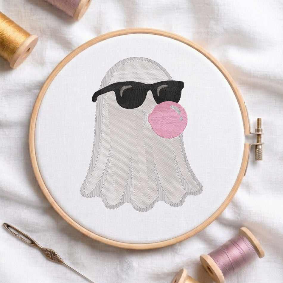 Cool white ghost wearing black sunglasses and blowing a pink bubblegum bubble machine embroidery design displayed in a wooden hoop.