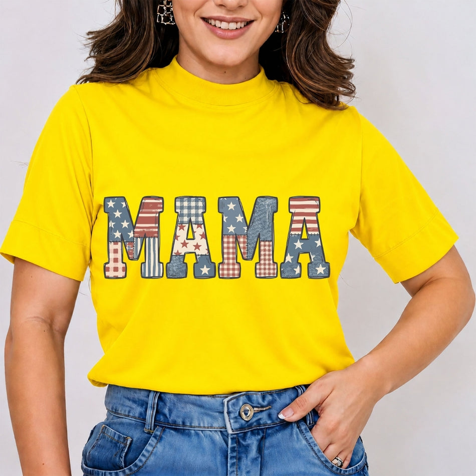 Woman wearing a bright yellow mock neck t-shirt featuring a "MAMA" varsity block letter graphic filled with 4th of July patriotic American flag stars and stripes patterns, tucked into blue jeans.