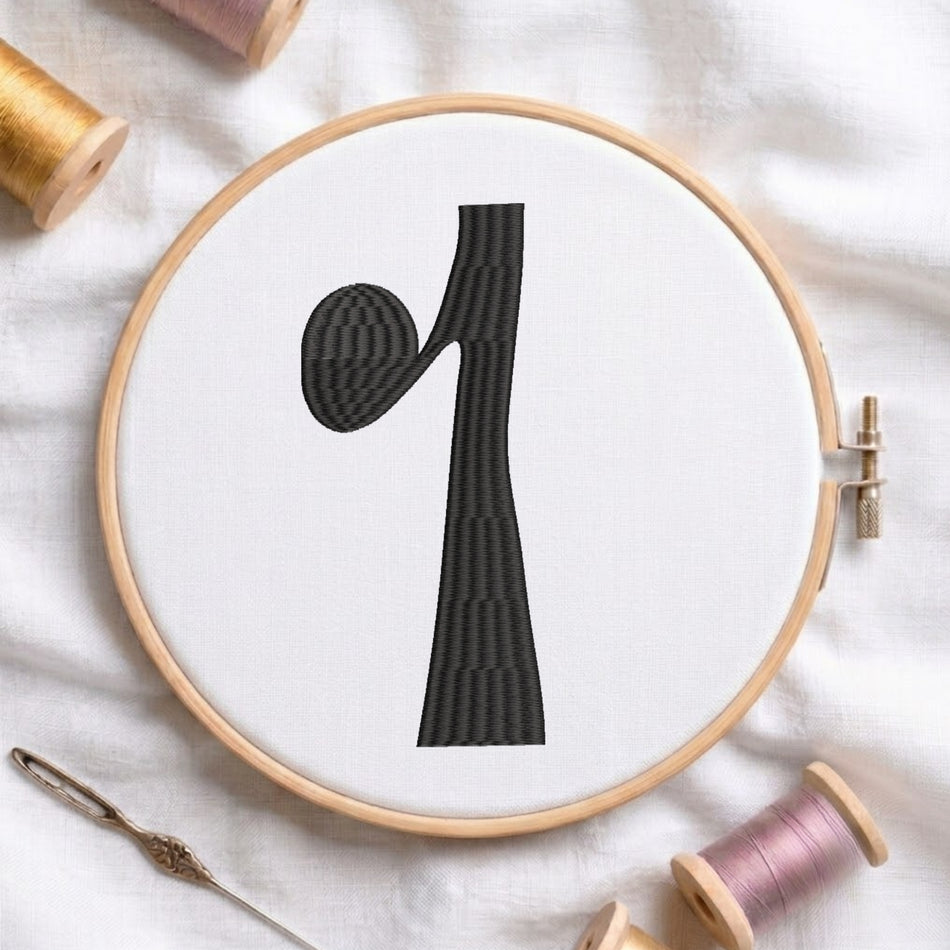 A circular embroidery hoop holding white fabric with a large black stylized letter 'q' design, surrounded by spools of thread and a needle on a white fabric background.