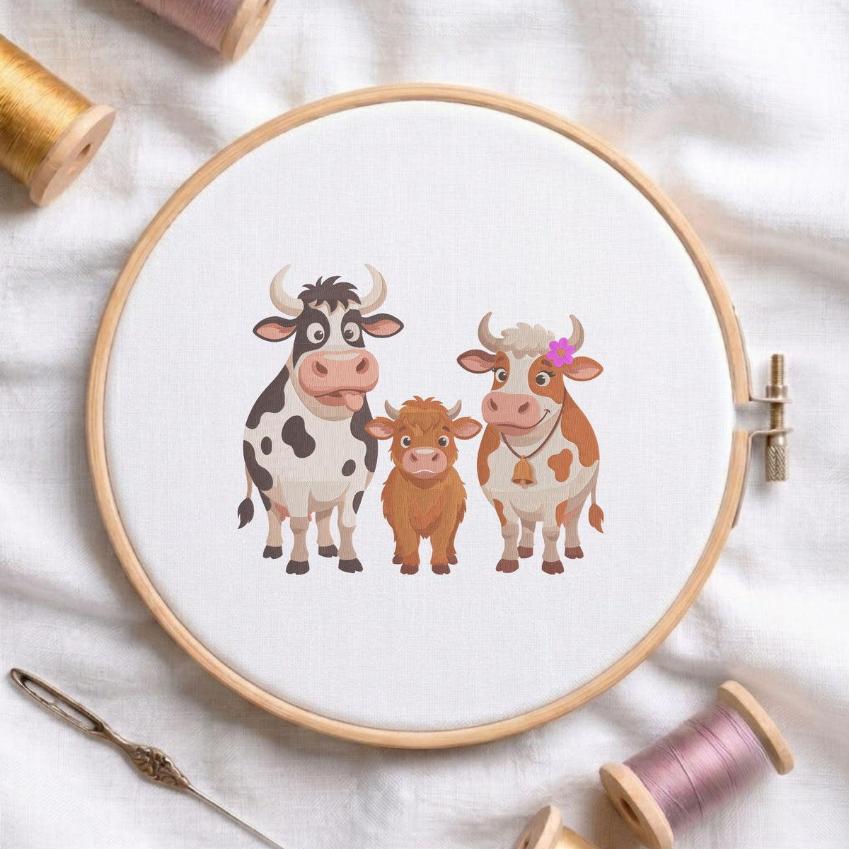 Cute farm animal cow family machine embroidery design displayed in a wooden embroidery hoop on white fabric with thread spools and a needle   