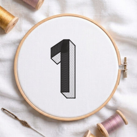 An embroidered 3D block number "1" with striped shading texture, stitched inside a wooden hoop on white fabric with sewing threads.