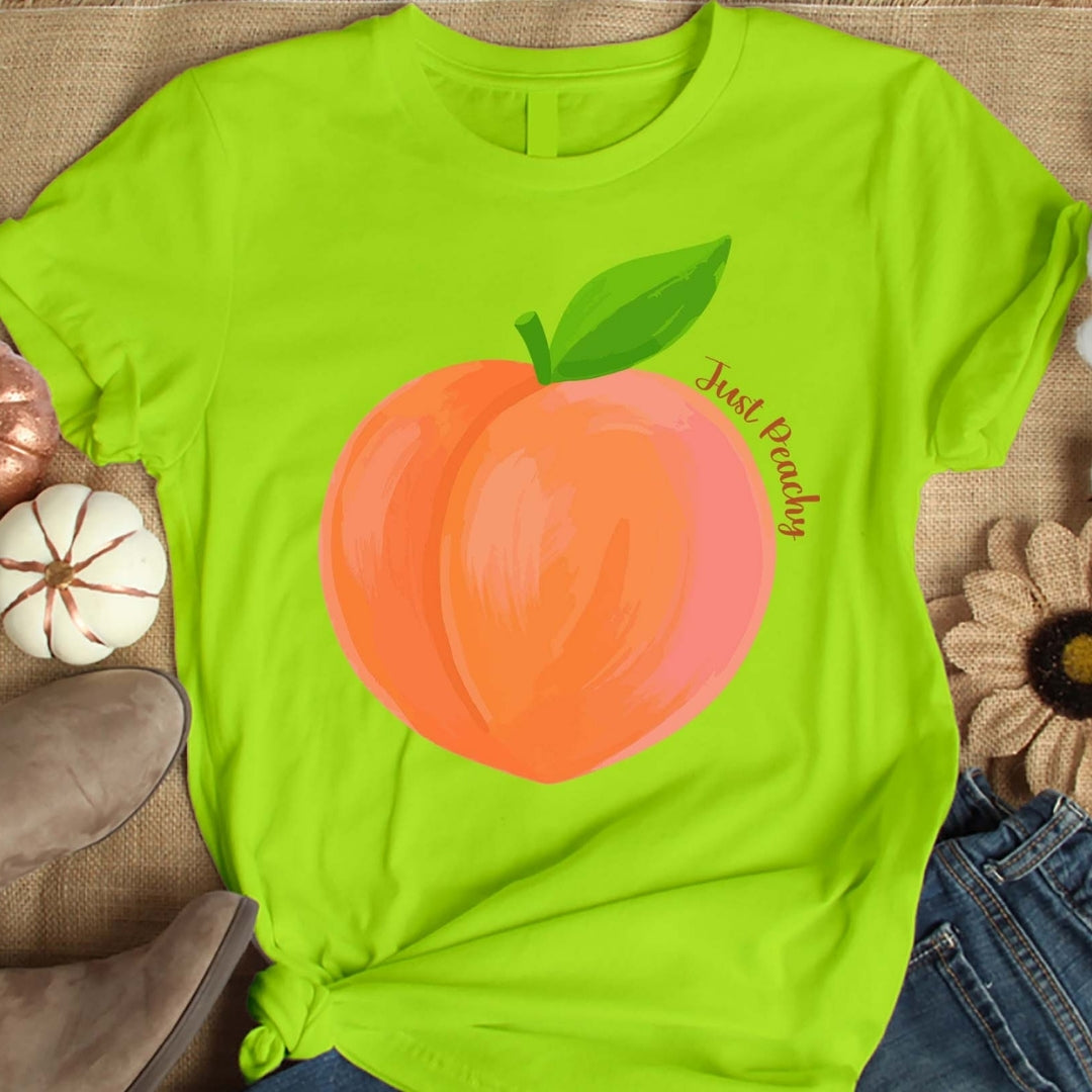 Green t-shirt with a peach graphic and 'Just Peachy' text on a textured surface.