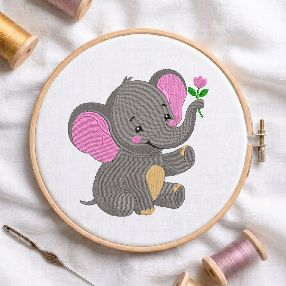 A circular embroidery hoop holding white fabric with a stitched cartoon elephant in gray and pink holding a small pink flower. The hoop is styled on a white fabric surface with spools of thread and a needle around it.