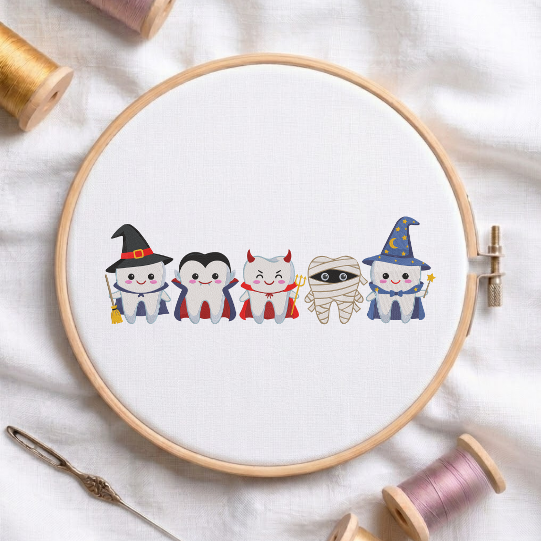 Cute Halloween teeth characters dressed as a witch, vampire, devil, mummy, and wizard machine embroidery design shown in a wooden embroidery hoop on white fabric with thread spools and a needle