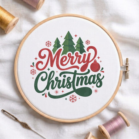 A circular embroidery hoop on white fabric, featuring a festive 'Merry Christmas' design with green trees, red lettering, and a red ornament. Spools of thread and a needle are arranged around it.