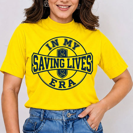 A woman wearing a bright yellow short-sleeve t-shirt with a navy blue graphic that reads 'IN MY SAVING LIVES ERA' with hockey icons, paired with blue jeans.