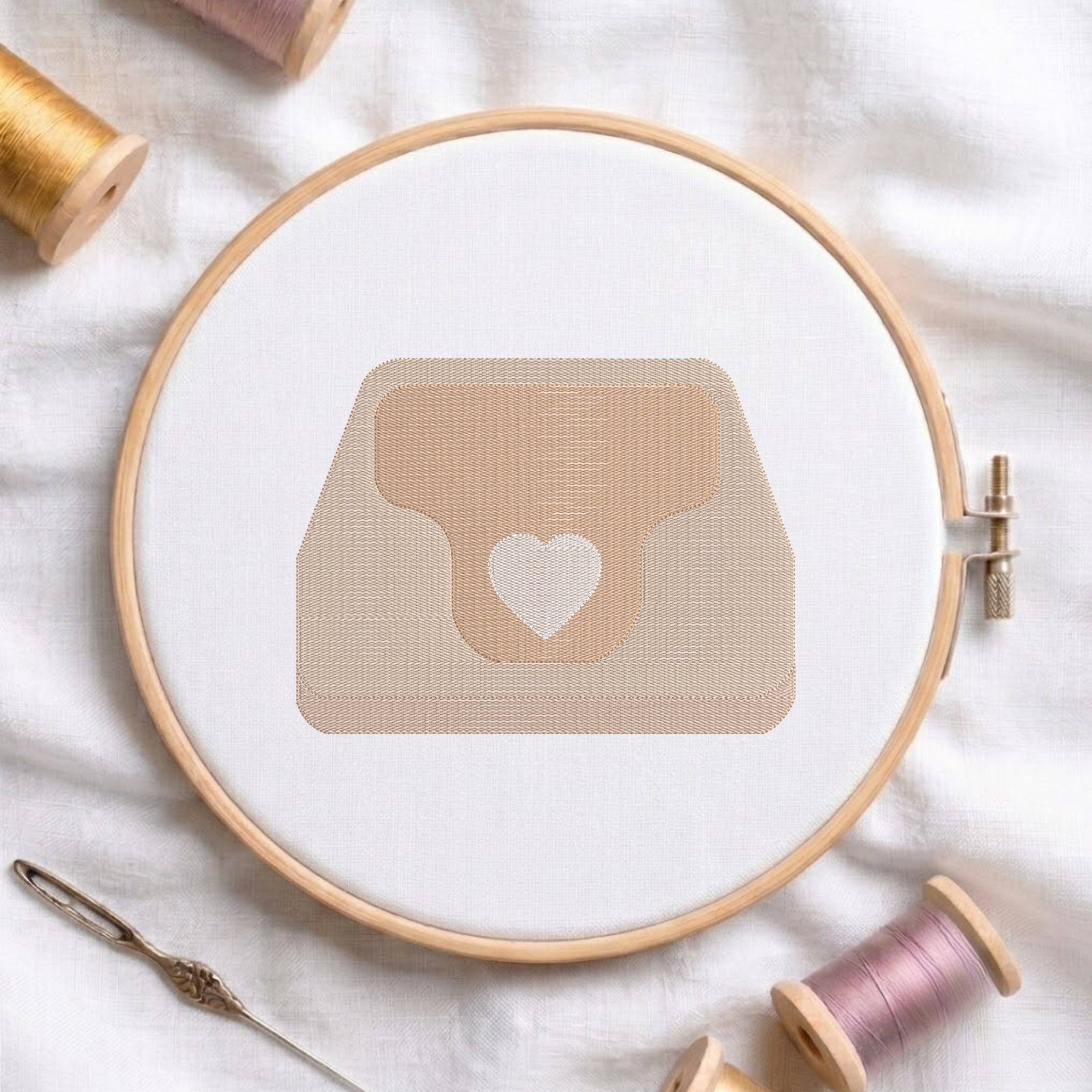 An embroidered heart purse design with a beige handbag and a white heart motif, stitched inside a wooden hoop on white fabric with sewing threads.