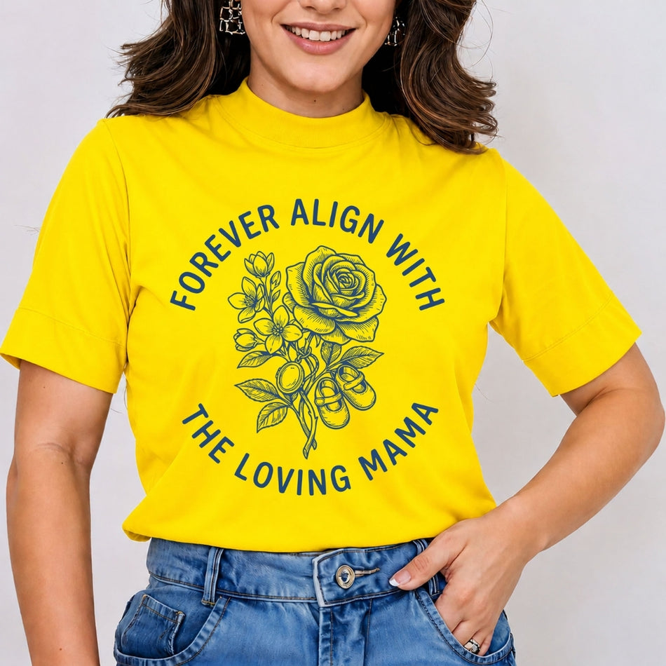 Woman wearing a bright yellow mock neck t-shirt featuring a blue retro line art graphic of a rose bouquet and baby shoes with the text "Forever Align with the Loving Mama", tucked into jeans.