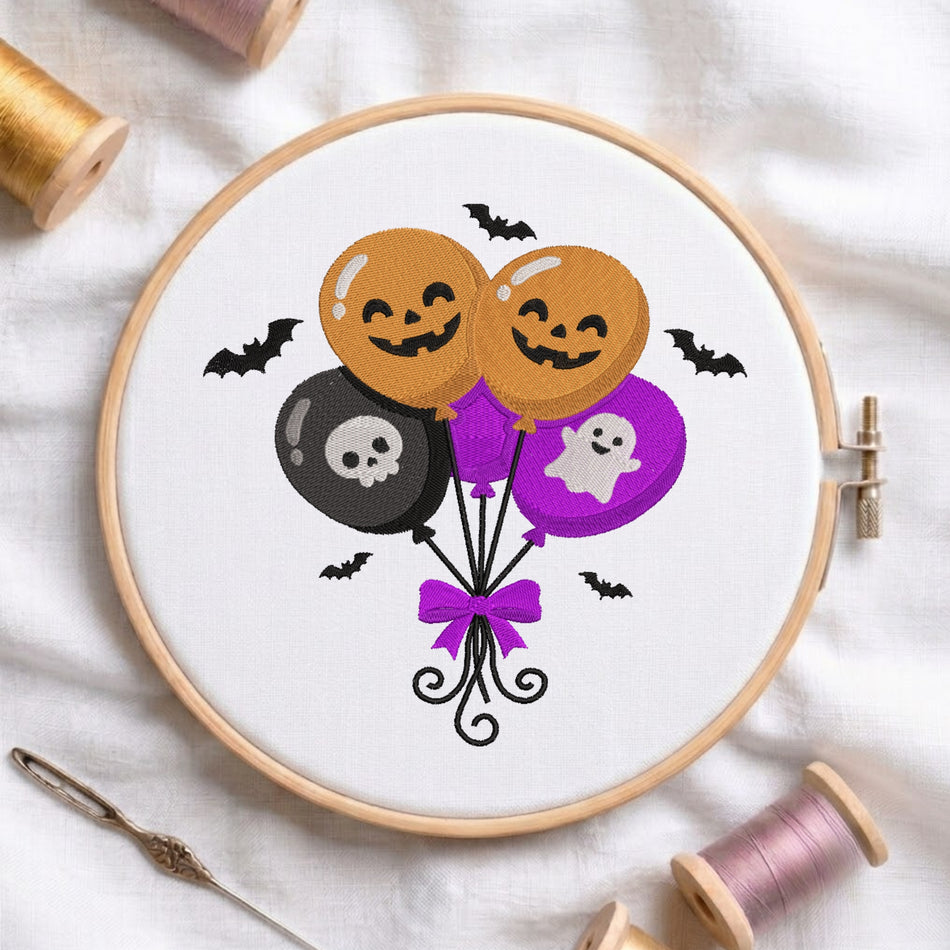 Halloween embroidery design featuring cute jack-o'-lantern pumpkins, skull, ghost, and flying bats in an embroidery hoop with spools of thread.