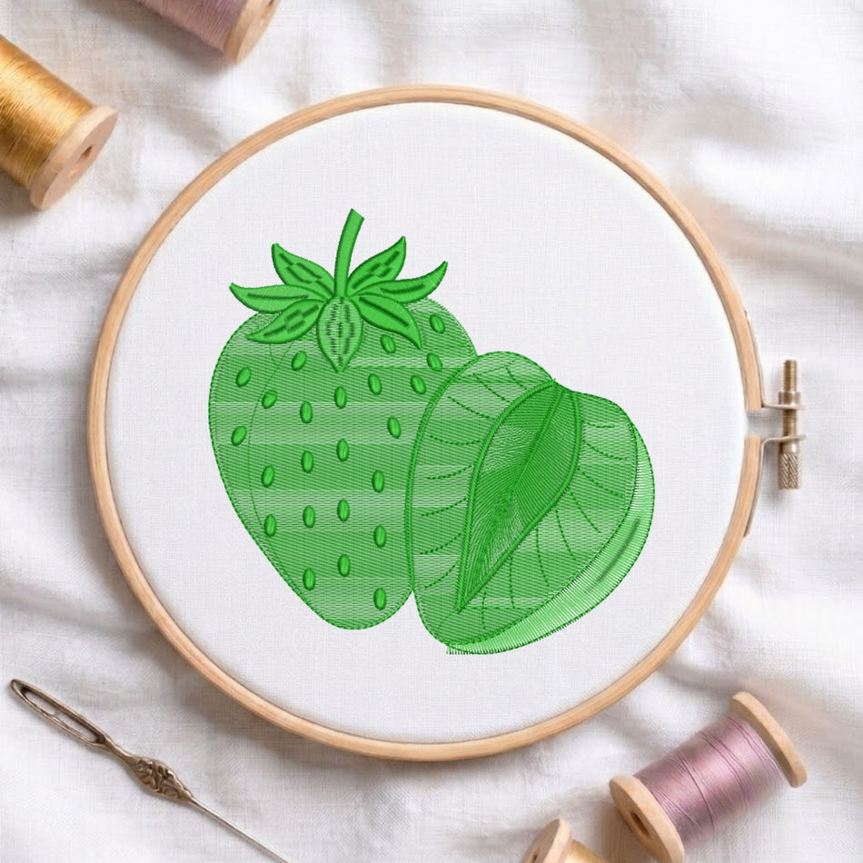 A wooden embroidery hoop holding white fabric with a green embroidered strawberry design, surrounded by spools of thread and a needle on a white fabric background.
