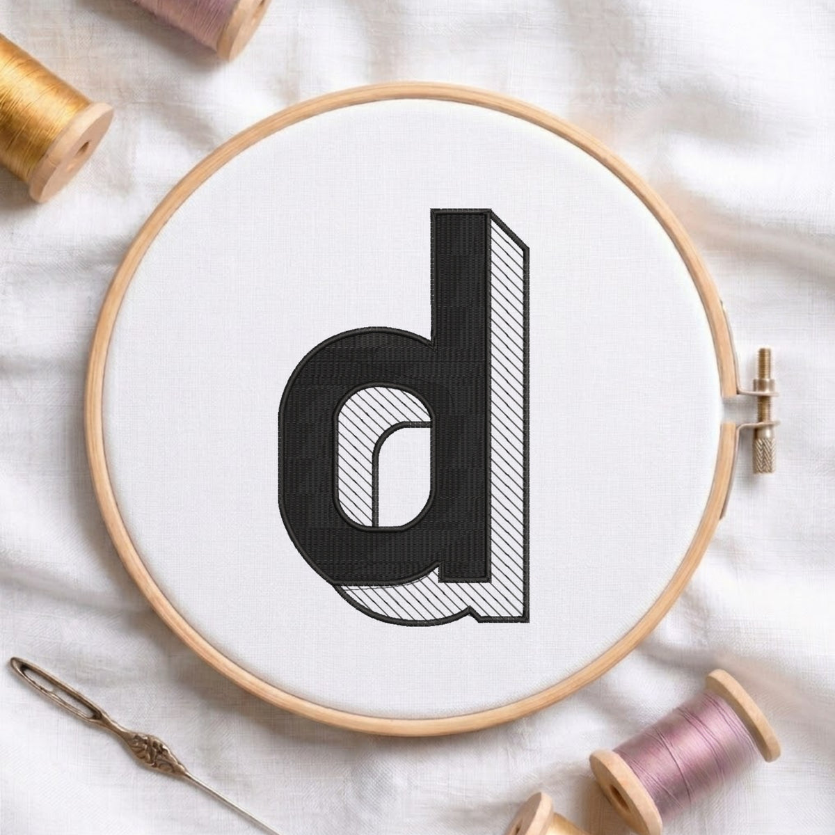 An embroidered 3D block lowercase letter "d" with striped shading texture, stitched inside a wooden hoop on white fabric with sewing threads.