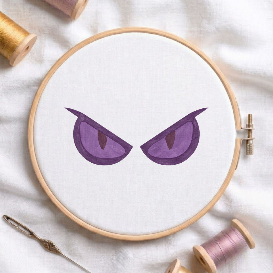 Dark purple expressive evil eyes embroidery pattern displayed inside a wooden embroidery hoop on white fabric.