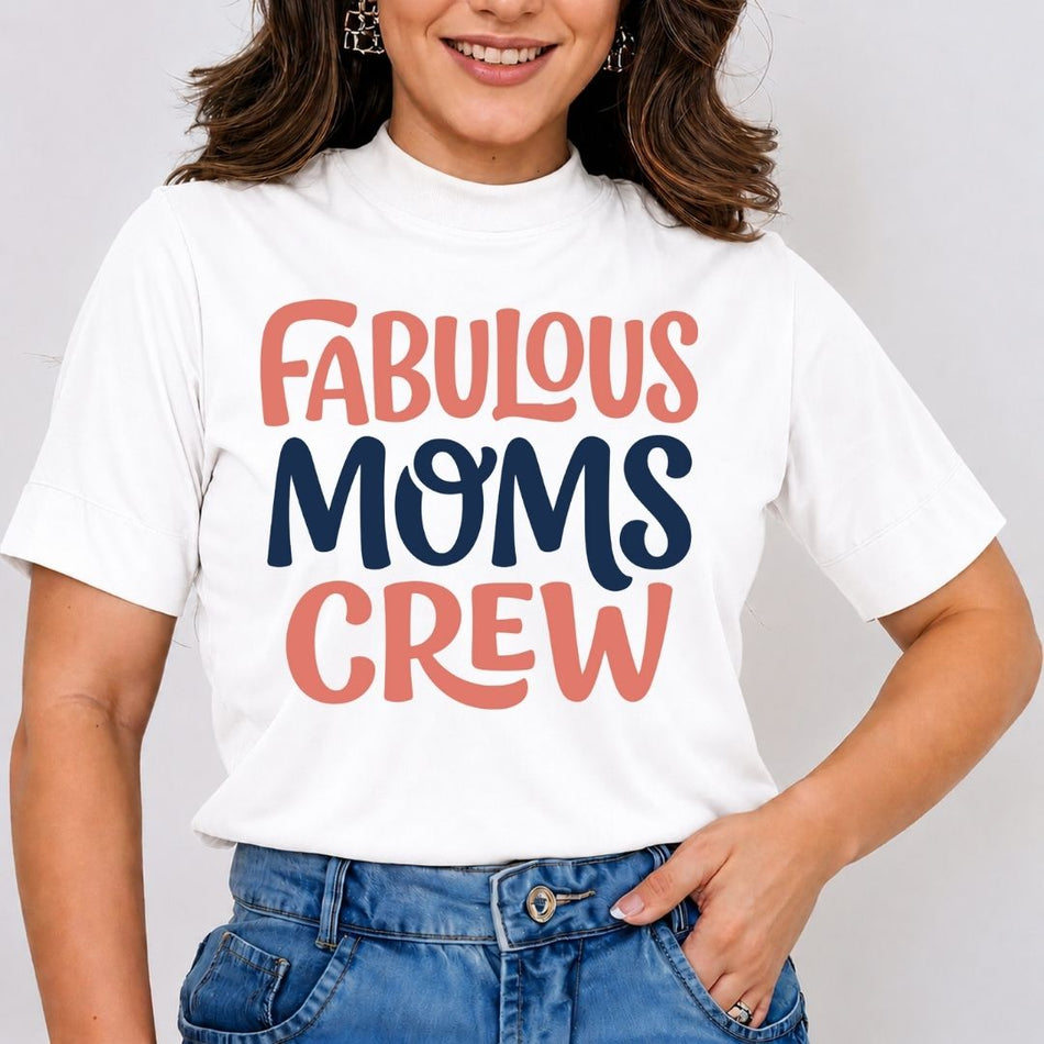 A woman wearing a white short-sleeve t-shirt with the text 'FABULOUS MOMS CREW' printed on the front in coral pink and navy blue lettering, paired with blue jeans.