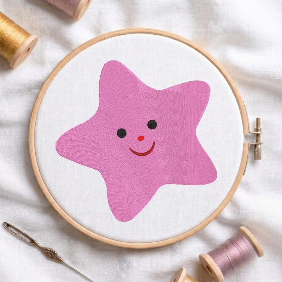 Cute pink star with a smiling face machine embroidery design displayed in a wooden hoop.