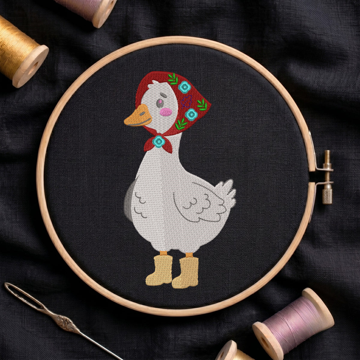 Goose wearing a red floral kerchief babushka and yellow rainboots embroidery design inside a wooden hoop on dark fabric.