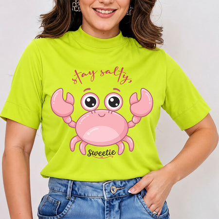 A person wearing a bright lime-green t-shirt with a cartoon pink crab graphic and the text "stay salty, Sweetie" printed on the front.