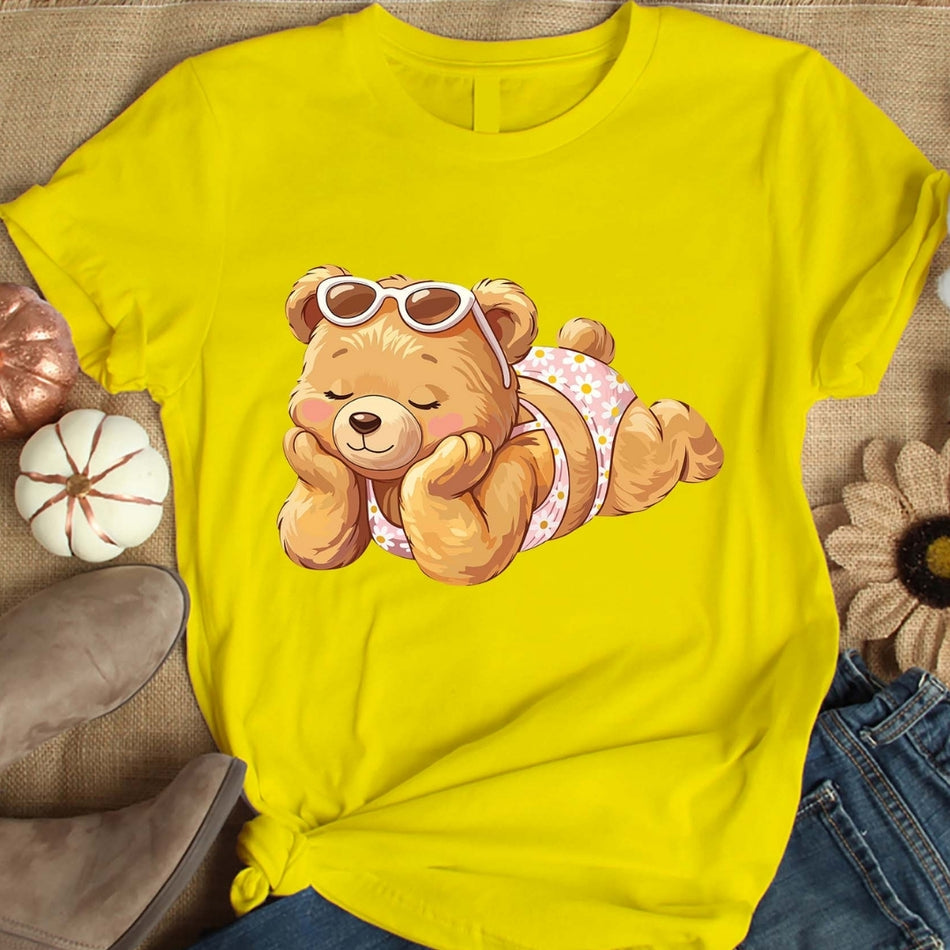 Yellow t-shirt with a teddy bear graphic on a textured surface