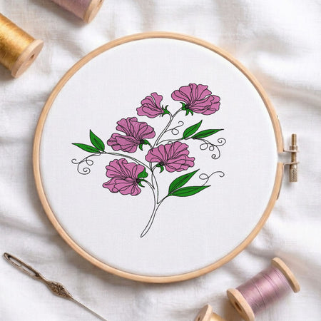 Sweet pea flower embroidery design inside a wooden hoop showing pink blossoms, green leaves, and black line work.