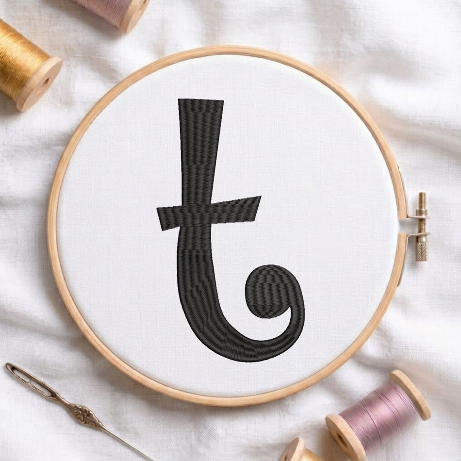 A wooden embroidery hoop holding white fabric with a large black embroidered letter 't' in a textured pattern. The hoop is styled on a white fabric background with spools of thread and a needle.