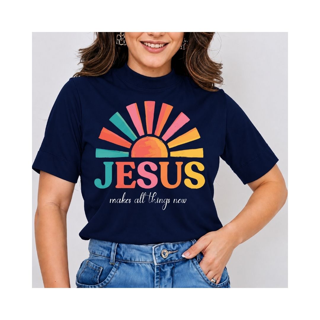 A woman wearing a navy blue graphic t-shirt with a colorful sunburst and the text 'JESUS makes all things new' in pink, orange, yellow, and teal, paired with blue jeans.