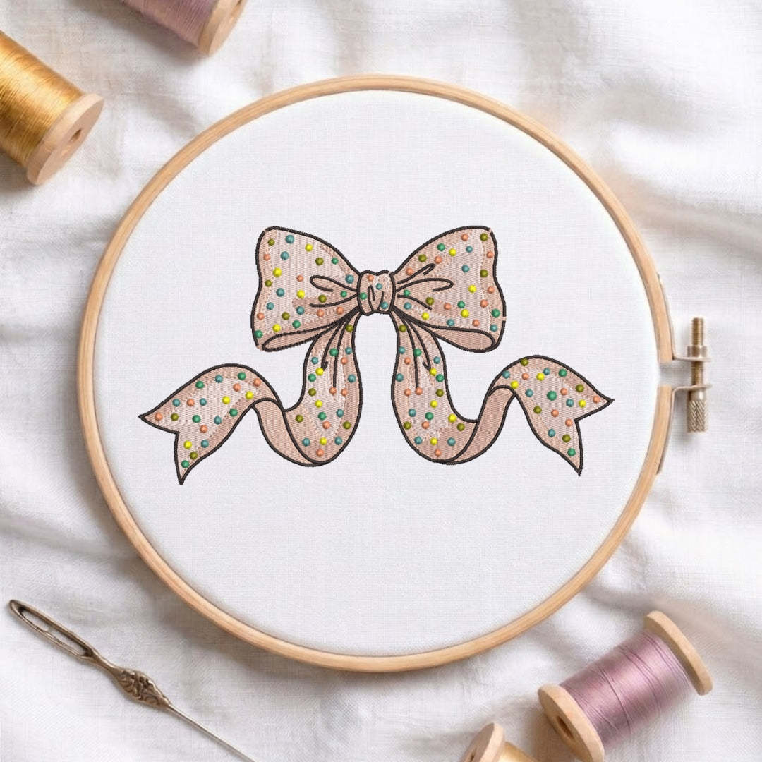 Polka dot ribbon bow machine embroidery design displayed in a wooden hoop.