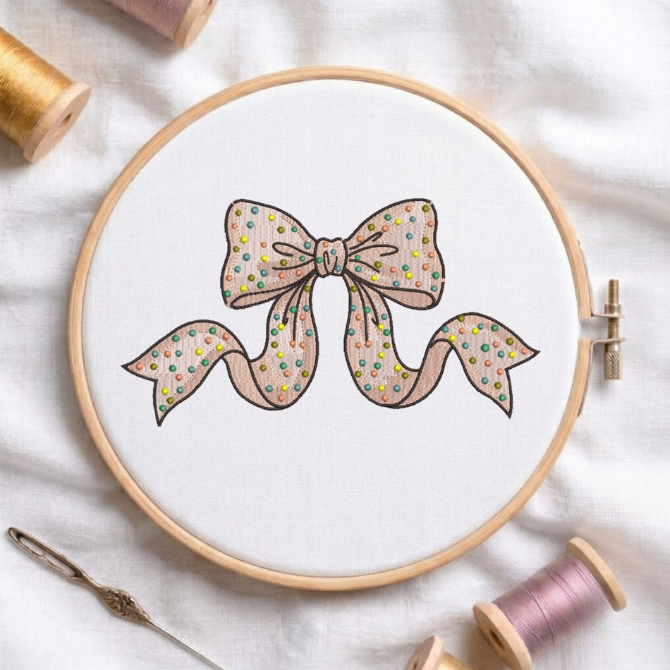 Polka dot ribbon bow machine embroidery design displayed in a wooden hoop.