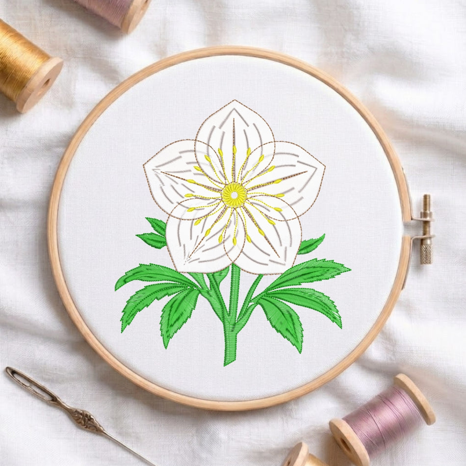 A circular embroidery hoop holding white fabric with a stitched white flower, green leaves, and a yellow center, surrounded by spools of thread and a needle on a white fabric background.