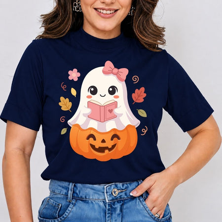 A woman wearing a navy blue short-sleeve t-shirt with a cute cartoon graphic of a white ghost reading a pink book on top of an orange jack-o'-lantern pumpkin, paired with blue jeans.