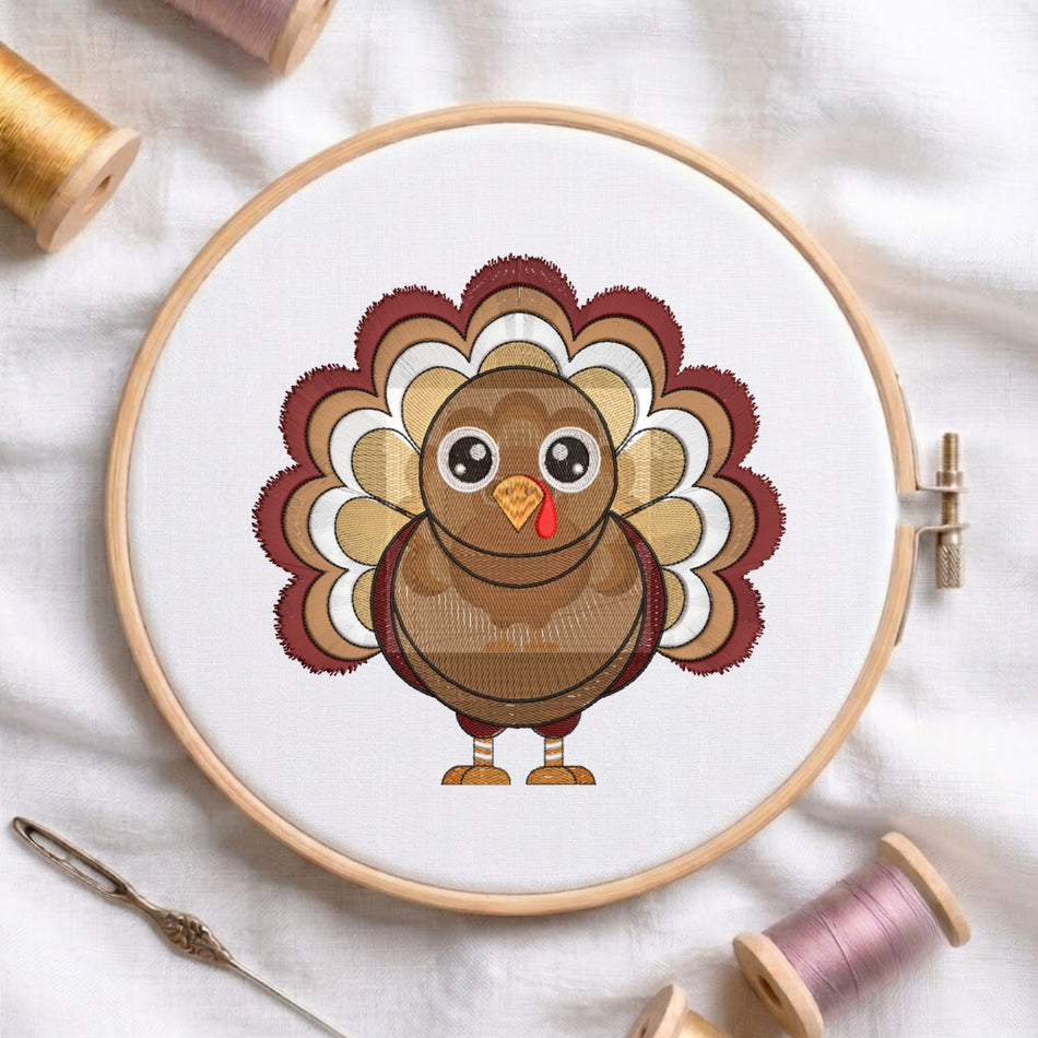 A circular embroidery hoop on white fabric displays a cartoon turkey design with layered brown, tan, cream, and burgundy feathers. Spools of thread and a needle are arranged around it on a white cloth background.