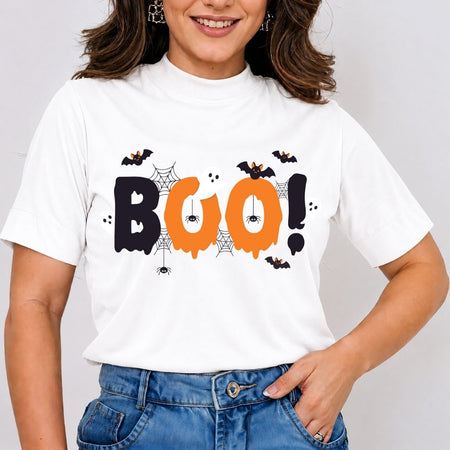 Woman wearing a white t-shirt featuring a spooky "BOO!" Halloween text design with bats, spiders, and webs.