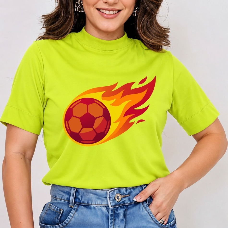 A woman smiling while wearing a lime green mock neck t-shirt printed with a vibrant cartoon flaming soccer ball illustration trailing red and orange flames.