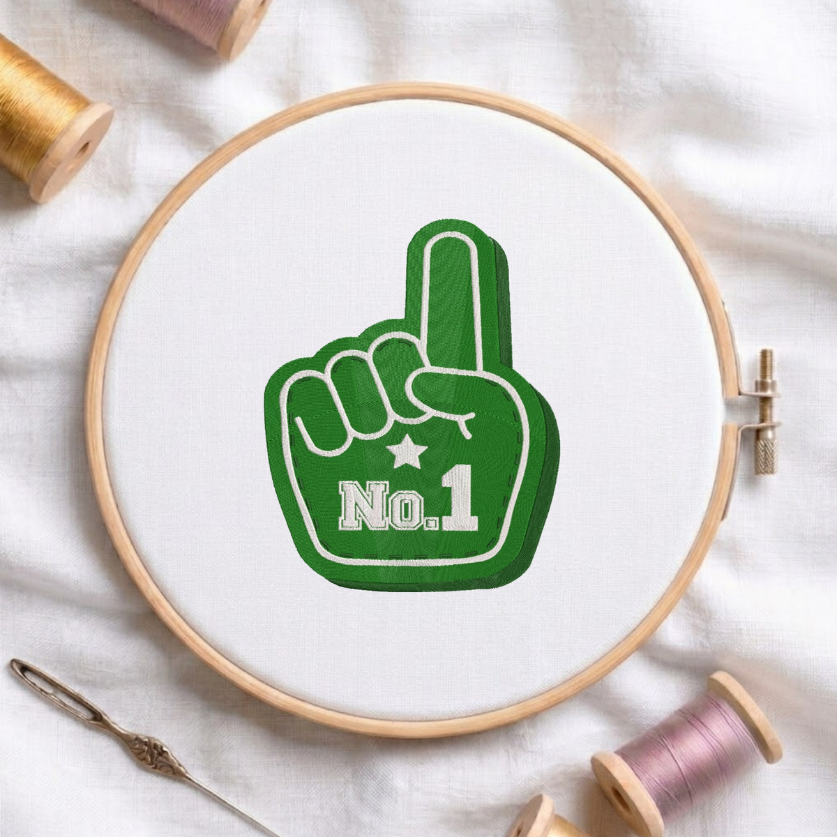 A circular embroidery hoop on white fabric, featuring a green foam finger graphic with the text 'No.1' in white.