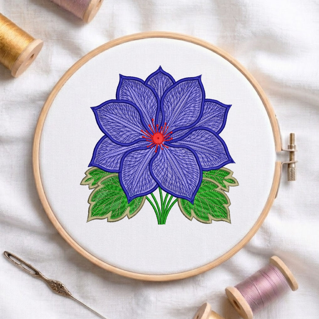 A circular embroidery hoop holding white fabric with a stitched flower design in purple, green, and red, surrounded by spools of thread and a needle on a white fabric background.