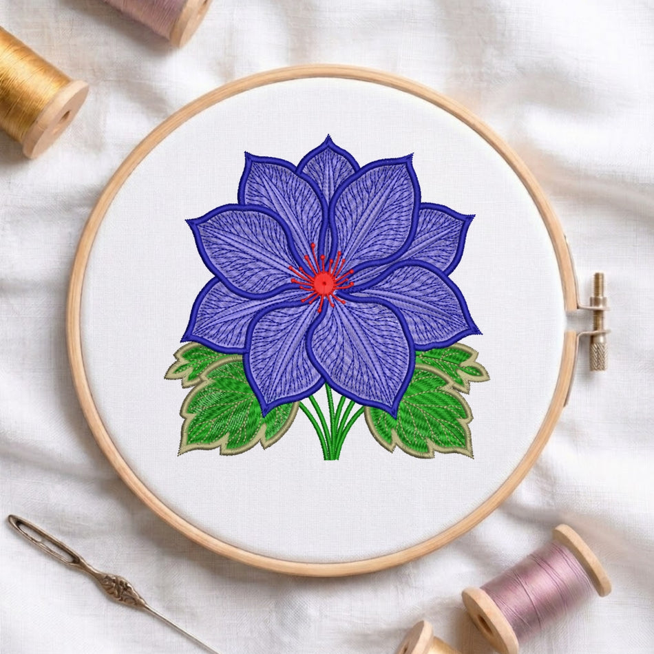 A circular embroidery hoop holding white fabric with a stitched flower design in purple, green, and red, surrounded by spools of thread and a needle on a white fabric background.