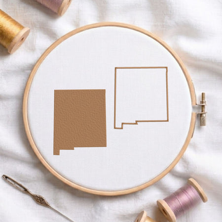  New Mexico state map fill and outline machine embroidery design, displayed in a wooden hoop on white fabric with thread spools and a needle.   