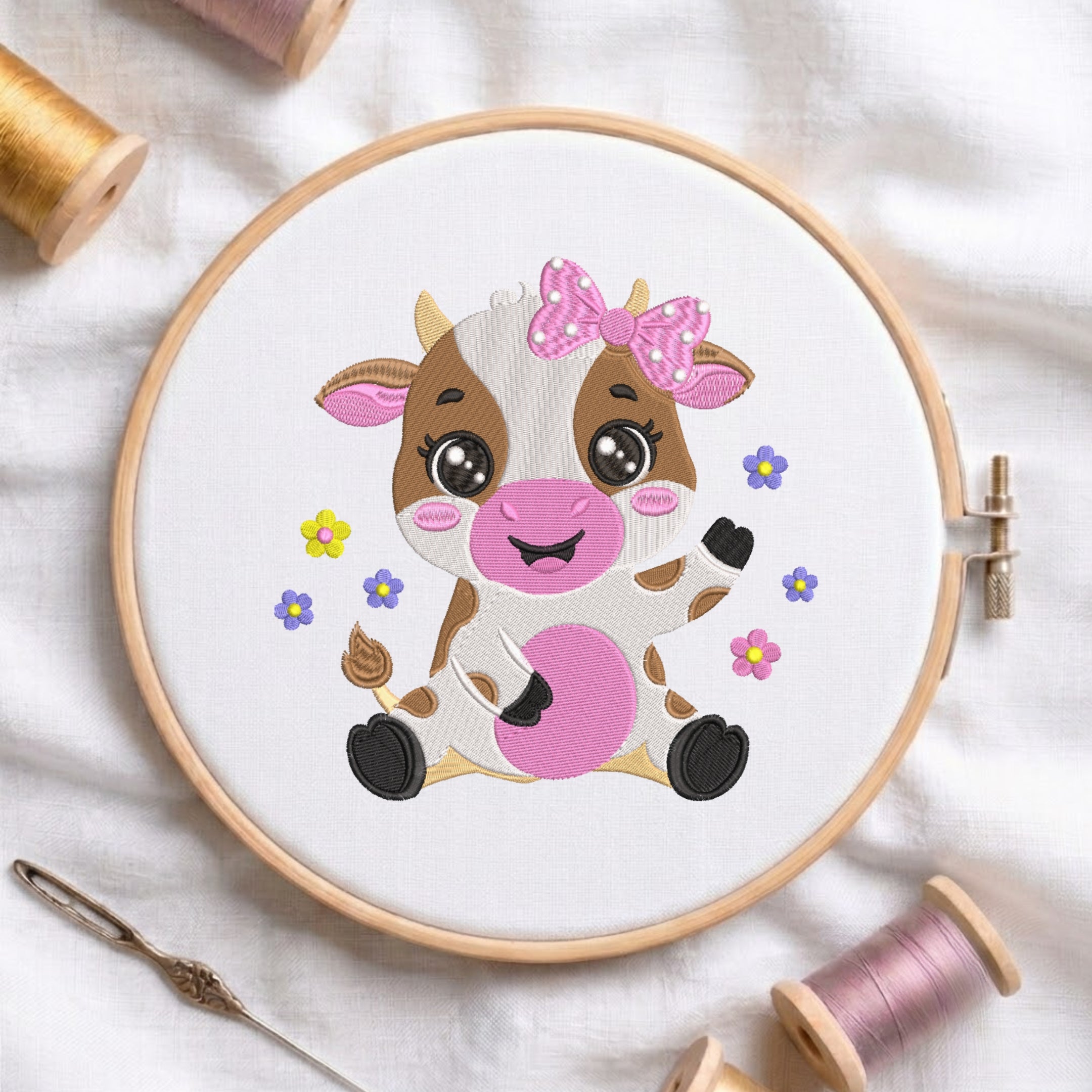 An embroidered design of a cute sitting baby cow with brown patches, big shiny eyes, a pink floral bow, and colorful flowers, stitched inside a wooden hoop on white fabric with sewing threads.